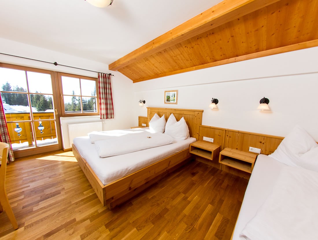 Schlafzimmer mit Doppelbett und Einzelbett und Balkon mit Pistenblick