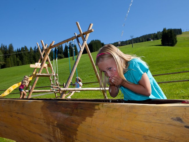 Schaukeln macht durstig - Erfrischung aus dem Trinkwasserbrunnen vor dem Haus